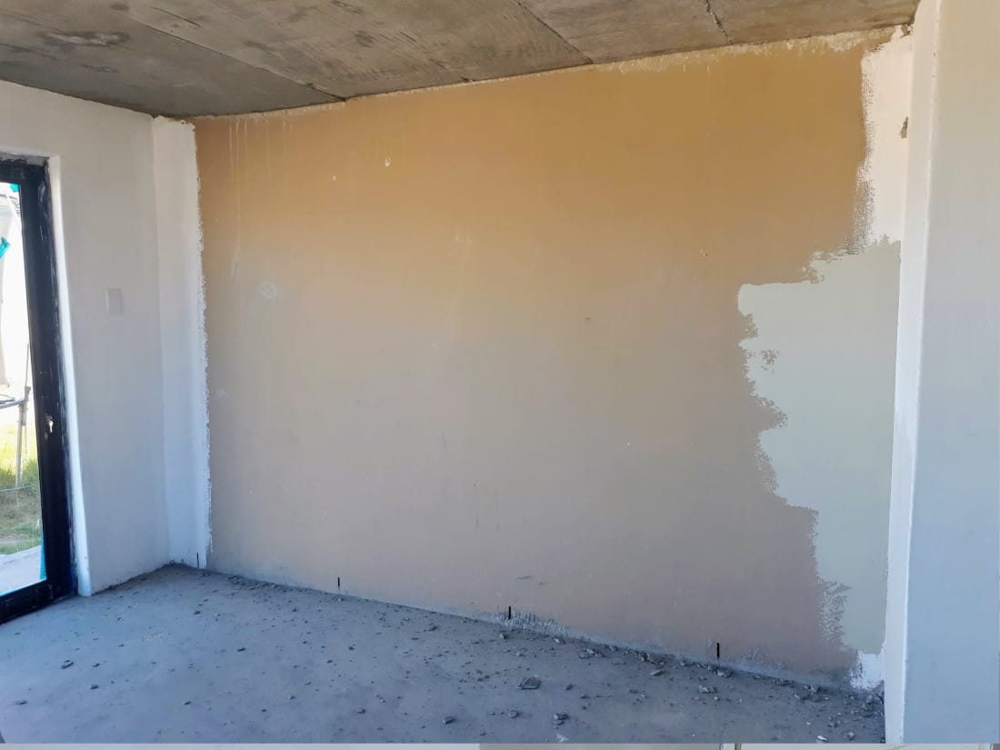 Room mid preparation, wall transitioning from raw plaster colour to a pale primer coat on the right