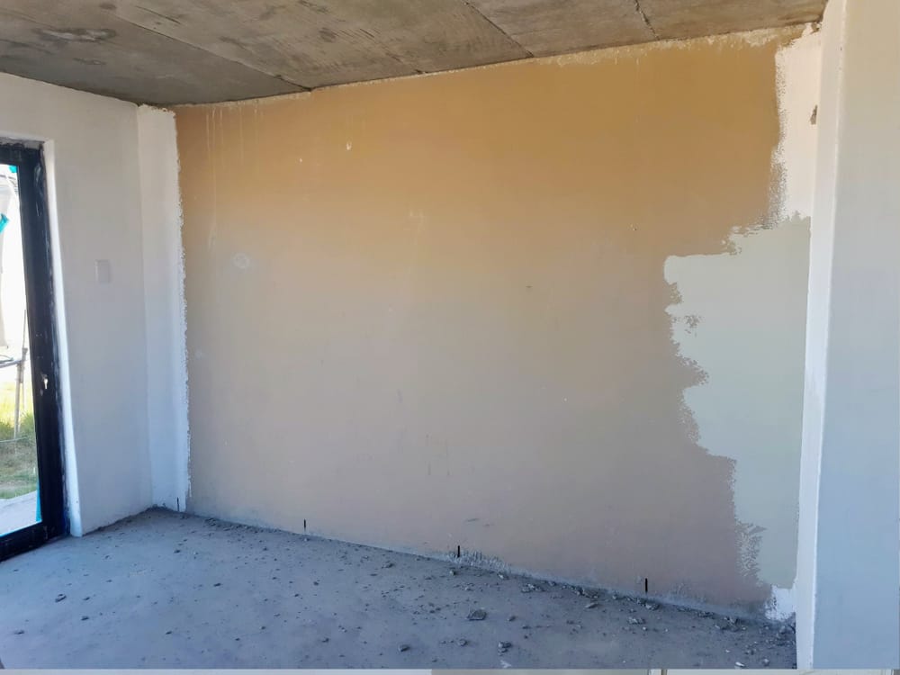 Room mid preparation, wall transitioning from raw plaster colour to a pale primer coat on the right